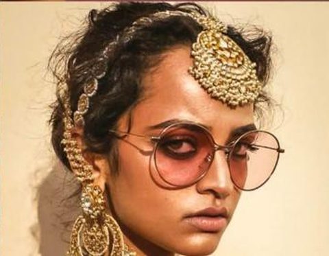Round rose-tinted glasses with a maang tikka and chandelier earring